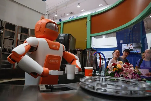 Visitors look at a robot making drinks during the 2018 World Robot conference in Beijing, China, 15 August 2018. (Photo by Roman Pilipey/EPA/EFE/Rex Features/Shutterstock)