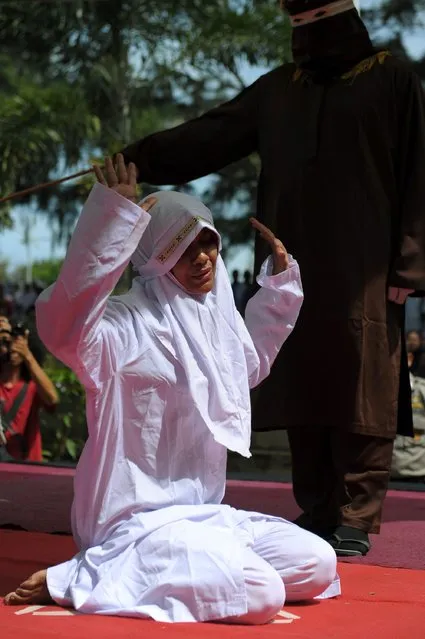 A religious officer canes an Acehnese woman (L) for spending time in close proximity with a man who is not her husband, which is against Sharia law, in Banda Aceh on November 28, 2016. (Photo by Chaideer Mahyuddin/AFP Photo)