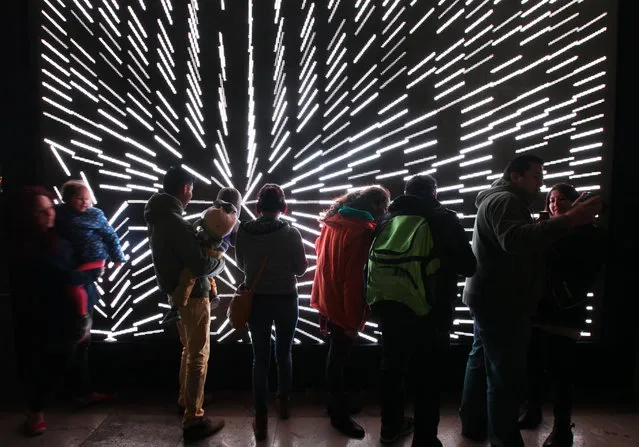 People gather to watch as a light show is projected on the facade of the Palace of Fine Arts at Alameda Park, in Mexico City, Friday, February 6, 2015. The show is part of the Visual Art Week Festival, organized by city authorities and will run from February 3-8. (Photo by Marco Ugarte/AP Photo)