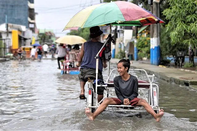 A boy rides on a rickshaw wading through a flooded street in the aftermath of typhoon Doksuri, in Valenzuela, Metro Manila, Philippines on July 27, 2023. (Photo by Eloisa Lopez/Reuters)