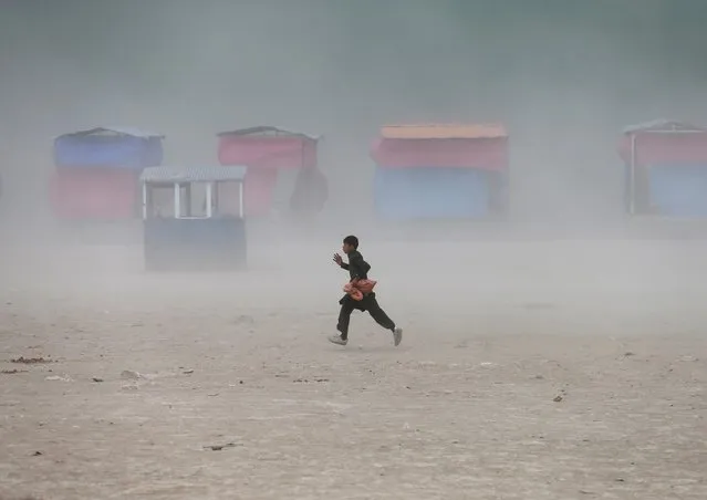 A boy runs during a dust storm at the Qargha Lake, on the outskirts of Kabul, Afghanistan April 20, 2021. (Photo by Mohammad Ismail/Reuters)