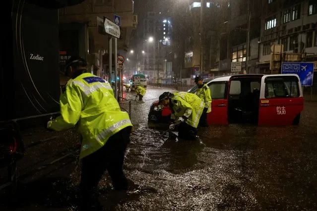 Police attempt to clear debris outside a drainage channel at a flooded area during heavy rain in Hong Kong, China on September 8, 2023. (Photo by Tyrone Siu/Reuters)