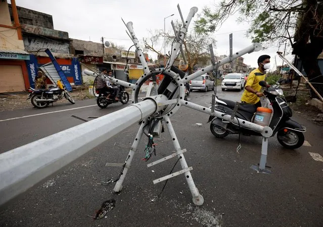 Motorcyclists move past a fallen street light pole after cyclone Tauktae hit, in Una, in the western state of Gujarat, India, May 18, 2021. (Photo by Amit Dave/Reuters)
