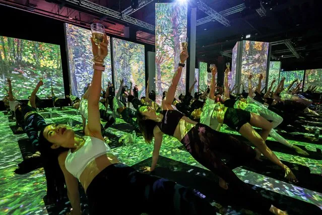 Yoga enthusiasts perform a yoga exercise in a wine yoga class inside “Van Gogh: The Immersive Experience”, a multi-sensorial exhibition featuring artworks of renowned artist Vincent van Gogh at a department store in Bangkok, Thailand, August 5, 2023. (Photo by Athit Perawongmetha/Reuters)