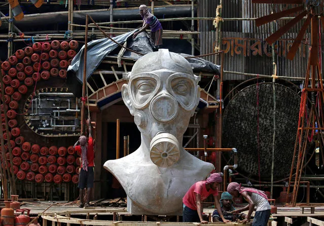 Labourers work in front of a giant sculpture of a man wearing a gas mask that will be used to decorate an “Open Air” themed pandal (temporary platform) for the upcoming Hindu festival of Durga Puja in Kolkata, India, September 28, 2018. According to organizers, the theme of the pandal seeks to create awareness on the importance of clean, unpolluted air, to devotees of Goddess Durga. (Photo by Rupak De Chowdhuri/Reuters)