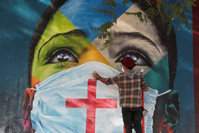 Brazilian graffiti artist Eduardo Kobra puts the final touches to his mural “Coexistencia – Memorial da Fe por todas as vitimas do Covid-19”, translated as “Coexistence – Memorial of Faith for all victims of Covid-19”, which portrays children of different religions wearing protective face masks, in Sao Paulo, Brazil on May 5, 2021. (Photo by Amanda Perobelli/Reuters)