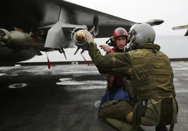 In this Wednesday, March 18, 2015 photo, a French pilot checks the bombs on his military plane before taking off from the flight deck of the French Navy aircraft carrier Charles de Gaulle in the Persian Gulf. (Photo by Hasan Jamali/AP Photo)