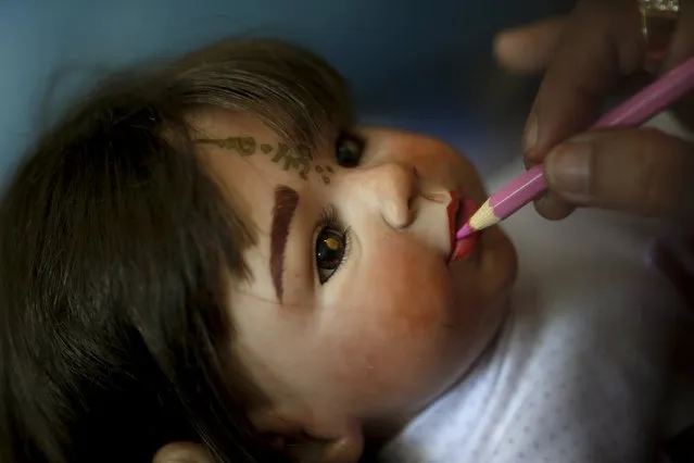 Mananya Boonmee, 49, works on the make-up of a “child angel” doll at her house in Nonthaburi, Thailand, January 26, 2016. (Photo by Athit Perawongmetha/Reuters)