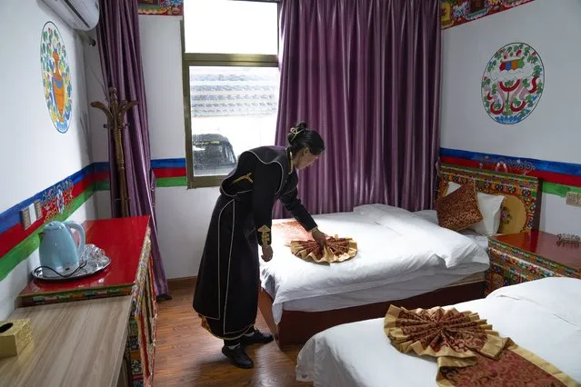 A woman in ethnic dress adjusts a bedspread at her tourist homestay in Zhaxigang village near Nyingchi in western China's Tibet Autonomous Region, Friday, June 4, 2021. Tourism is booming in Tibet as more Chinese travel in-country because of the coronavirus pandemic, posing risks to the region's fragile environment and historic sites. (Photo by Mark Schiefelbein/AP Photo)