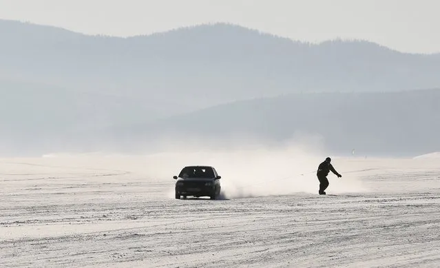 A car tows a snowboarder along the frozen surface of the Yenisei River in Taiga district, with the air temperature at about minus 25 degrees Celsius (minus 13 degrees Fahrenheit), outside Krasnoyarsk, Siberia, Russia, January 31, 2016. (Photo by Ilya Naymushin/Reuters)