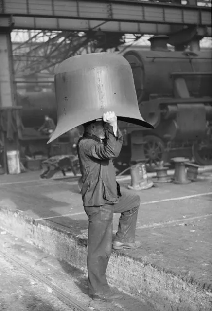 A workman carrying an engine dome at a locomotive works in Crewe, March 9, 1936. (Photo by William Vanderson/Fox Photos/Getty Images)