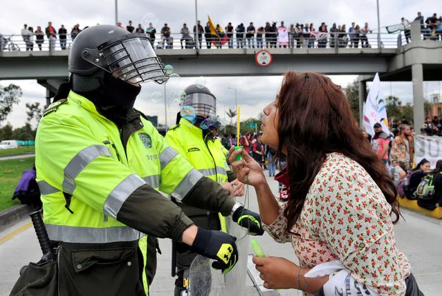A student blows soap bubbles at a policeman during a march to demand more resources from the government to finance public education, in Bogota, Colombia November 28, 2018. (Photo by Carlos Julio Martinez/Reuters)
