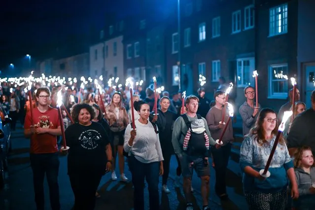 People carry torches during the Bridport Torchlight Procession, on August 21, 2022 in Bridport, England. The Bridport Torchlight Procession has been the traditional finale to Bridport Carnival week since 1971 with up 4000 people parading from Bucky Doo Square in Bridport to West Bay. (Photo by Finnbarr Webster/Getty Images)