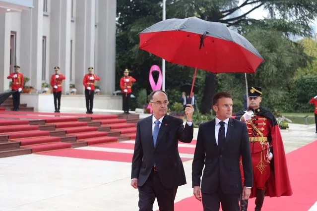 Albania's President Bajram Begaj (L) holds an umbrella during the inspection of the honor guard with French President Emmanuel Macron (R) ahead of their meeting in Tirana, Albania, 17 October 2023. French President Macron is on an official visit to Albania. (Photo by Malton Dibra/EPA)