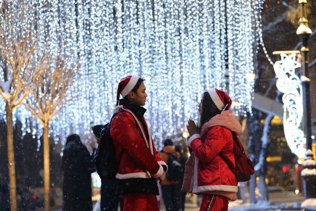 People dressed as Santa Claus stay next to the Christmas illuminations in Almaty, Kazakhstan December 20, 2018. (Photo by Pavel Mikheyev/Reuters)