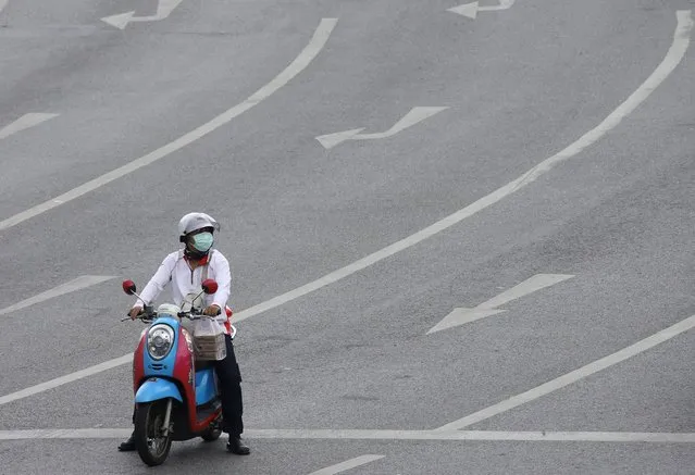 A person on a motorcycle stops at a red light in a nearly empty road in Bangkok, Thailand, 02 August 2021. The Thai government has imposed for 14 days, effective from 03 August 2021, a strict lockdown and curfew from 9pm to 4am in 29 provinces, including the capital Bangkok, as well as the tightening of health measures in a bid to curb the spread of COVID-19 infections. (Photo by Narong Sangnak/EPA/EFE)