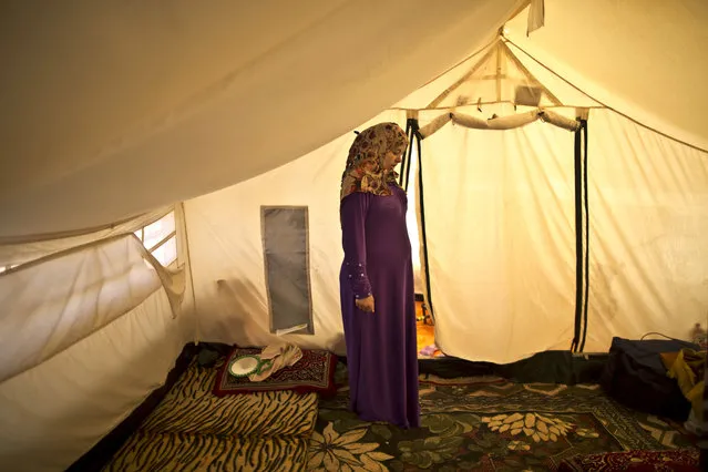 In this Tuesday, March 17, 2015 photo, Syrian refugee Adala Ismail, 32, who is six months pregnant, poses for a portrait inside her tent at an informal settlement near the Syrian border, on the outskirts of Mafraq, Jordan. (Photo by Muhammed Muheisen/AP Photo)