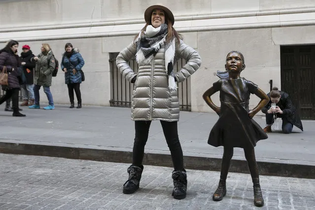 A woman poses with the “Fearless Girl” statue after it is unveiled at its new location in front of the New York Stock Exchange, Monday, December 10, 2018, in New York. The statue, considered by many to symbolize female empowerment, was previously located near the Charging Bull statue on lower Broadway. (Photo by Mark Lennihan/AP Photo)