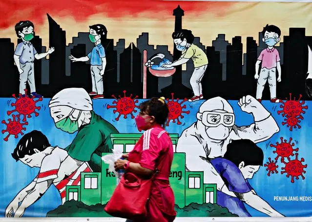 A woman wearing a protective face mask walks past a mural promoting awareness of the coronavirus outbreak, in Jakarta, Indonesia, June 24, 2021. (Photo by Ajeng Dinar Ulfiana/Reuters)