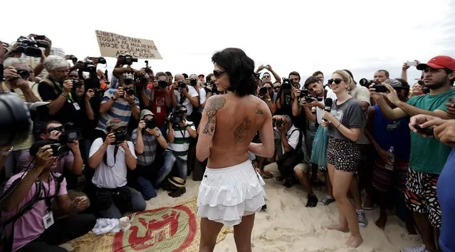 Media members surround a woman as she takes off her top as a protest on Ipanema beach in Rio de Janeiro, on December 21, 2013. The protest was aimed against what organizers say is the restraining of topless women on Rio de Janeiro's beaches. Local media reported that the protest was called after an actress was stopped by police officers while she was taking part, half naked, in a photo shoot on a beach to promote her play. (Photo by Ricardo Moraes/Reuters)