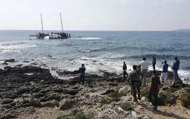 Greek Coast guard officers and locals look at a capsized sailboat with migrants onboard, who are trying to reach Greece, near the coast of the southeastern island of Rhodes April 20, 2015. A wooden sailboat carrying dozens of immigrants ran aground on Monday off the coast of the Greek island of Rhodes and at least three people have drowned, the Greek coast guard said. (Photo by Michalis Loizos/Reuters)