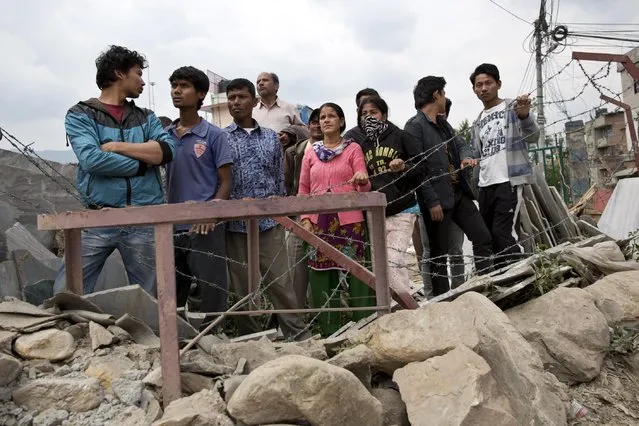 Locals gather to watch a rescue operation at the site of a budget hotel that collapsed in Saturday's earthquake, in Kalanki neighbourhood of Kathmandu, Nepal, Sunday, April 26, 2015. (Photo by Bernat Armangue/AP Photo)