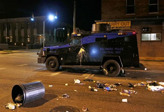 A police armoured car is pelted with garbage as it moves down a street as clouds of smoke and crowd control agents rise shortly after the deadline for a city-wide curfew passed in Baltimore, Maryland April 28, 2015, as crowds protest the death of Freddie Gray, a 25-year-old black man who died in police custody. (Photo by Shannon Stapleton/Reuters)