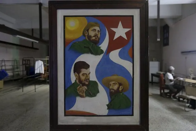 A painting shows images of Cuba's former president Fidel Castro (C), of revolutionary hero Ernesto “Che” Guevara (L) and Cuba's rebel hero Camilo Cienfuegos at a textile factory in Havana March 16, 2016. (Photo by Enrique de la Osa/Reuters)