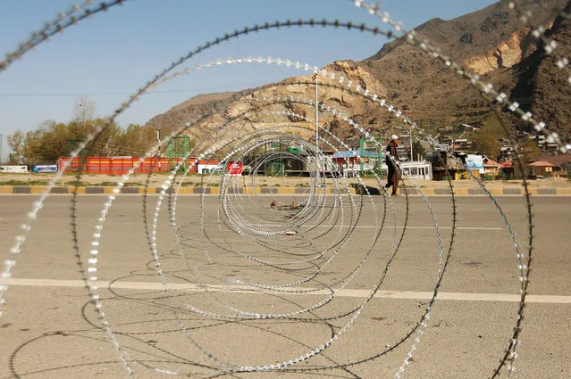 A man walks next to concertina wire laid across a national highway on the outskirts of Srinagar, April 7, 2019. (Photo by Danish Ismail/Reuters)
