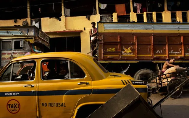 An Ambassador taxi makes its way through a busy street of Burrabazar wholesale market in Kolkata, India, Monday, March 21, 2016. The maker of the iconic Ambassador halted production on 2014 and gradually is replaced by newer models forcing its disappearance from Indian roads. (Photo by Bernat Armangue/AP Photo)