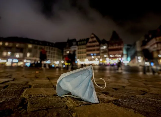 A face mask was left back on the Roemerberg square in Frankfurt, Saturday, November 6, 2021. (Photo by Michael Probst/AP Photo)
