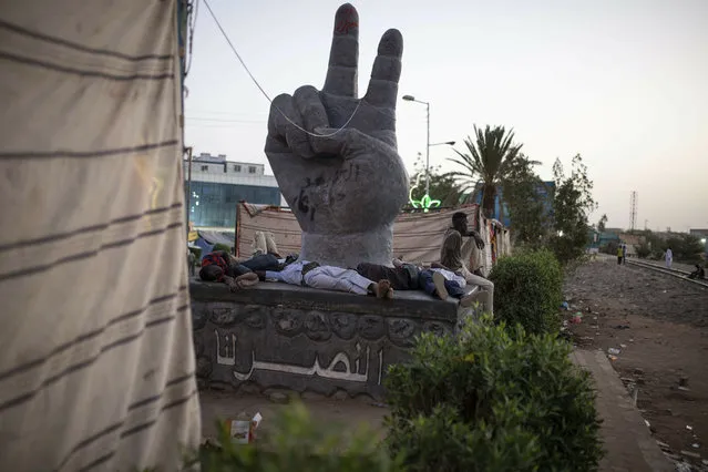 Protesters rest on the pedestal of a sculpture during a sit-in at Armed Forces Square in Khartoum, Sudan, Saturday, April 27, 2019. The Umma party of former Prime Minister Sadiq al-Mahdi, a leading opposition figure, said the protesters will not leave until there is a full transfer of power to civilians. (Photo by Salih Basheer/AP Photos)