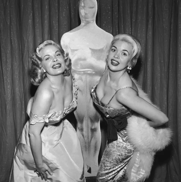 American actors Cleo Moore (1928 – 1973, left) and Jayne Mansfield (1933 – 1967) display their cleavage while posing in front of an Oscar likeness at the Academy Awards, RKO Pantages Theatre, Los Angeles, California on March 21, 1956. (Photo by Hulton Archive/Getty Images)