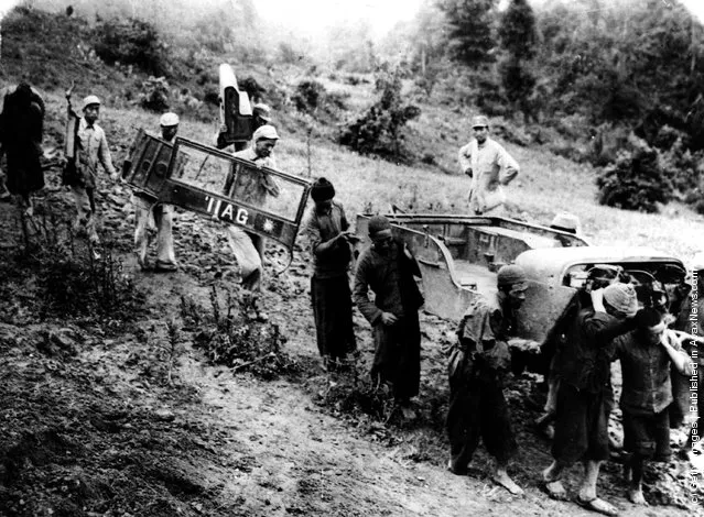 1939: Chinese soldiers and labourers carry parts of an American leased Jeep over mountain trails for re-assembly on the repaired section of the Burma Road in China