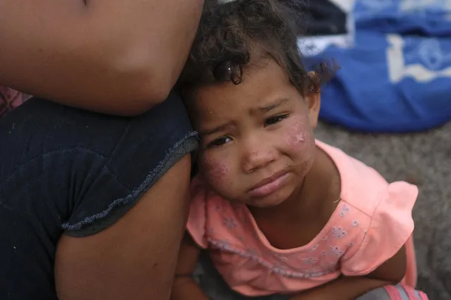 Venezuelan migrant Magdelis Alejos' daughter rests her head on her mother after the police told the family to break up the camp that they has set up on the seashore in El Morro, a neighborhood of Iquique, Chile, Sunday, December 12, 2021. (Photo by Matias Delacroix/AP Photo)
