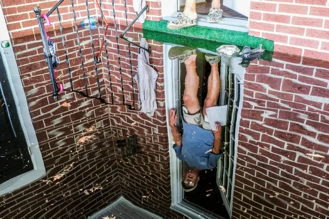 Floyd Boyd is reflected in floodwaters as he measures the water in his car port and finds it inches from entering his home on Sunday, September 23, 2018 in Conway, S.C. The Sherwood Drive area of Conway, S.C., began to look like a lake on Sunday as homes were submerged deeper than ever in flood waters that have already set historic records. (Photo by Jason Lee/The Sun News via AP Photo)