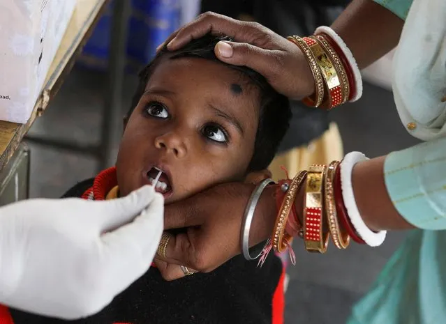 A healthcare worker collects a coronavirus disease (COVID-19) test swab sample from a child amidst the spread of the disease, at a railway station in New Delhi, India, December 22, 2021. (Photo by Anushree Fadnavis/Reuters)
