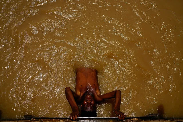 A Sudanese boy cools himself off in an irrigation channel near Khartoum, Sudan, June 19, 2019. (Photo by Umit Bektas/Reuters)