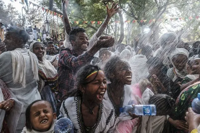 Ethiopian Orthodox worshippers get sprinkled with water in the compound of Fasilides Bath during the celebration of Timkat, the Ethiopian Epiphany, in the city of Gondar, Ethiopia, on January 19, 2022. (Photo by Eduardo Soteras/AFP Photo)