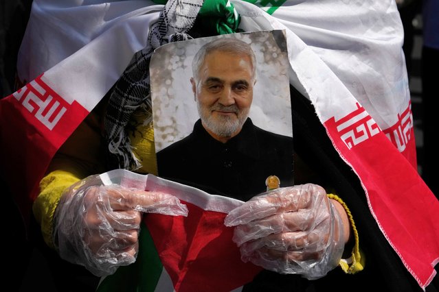 A worshipper holds a portrait of the late Iranian Revolutionary Guard Gen. Qassem Soleimani, who was killed in a U.S. drone attack in 2020 in Iraq, during an anti-Israeli gathering after Friday prayer in Tehran, Iran, Friday, April 19, 2024. An apparent Israeli drone attack on Iran saw troops fire air defenses at a major air base and a nuclear site early Friday morning near the central city of Isfahan, an assault coming in retaliation for Tehran's unprecedented drone-and-missile assault on the country. (Photo by Vahid Salemi/AP Photo)