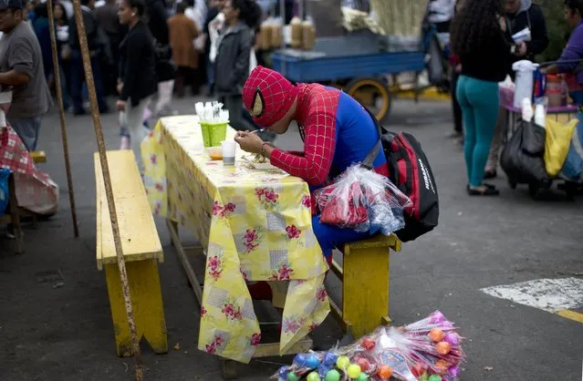 A street vendor dressed as Spiderman eats breakfast during a break during the Saint Peter celebrations in Lima, Peru, Monday, June 29, 2015. (Photo by Rodrigo Abd/AP Photo)
