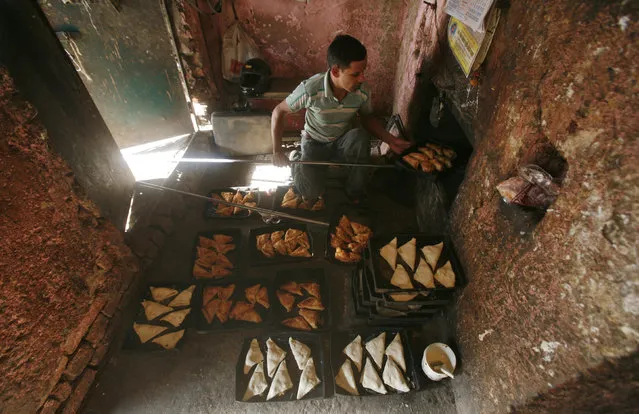 A worker takes out baked patties from an oven at a bakery at Noida in Uttar Pradesh January 20, 2011. (Photo by Parivartan Sharma/Reuters)