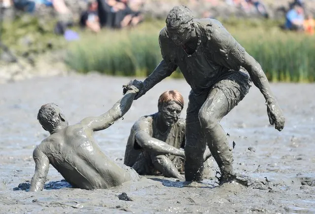 A player gets assistance by a team mate during their soccer match at the so called “Wattoluempiade” (Mud Olympics) in Brunsbuettel at the North Sea, July 11, 2015. (Photo by Fabian Bimmer/Reuters)
