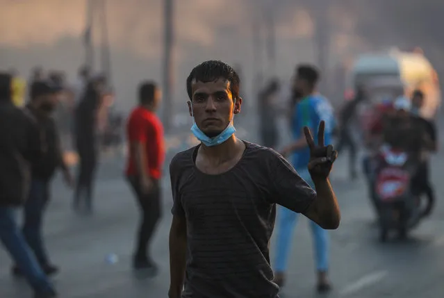 An Iraqi demonstrator gestures with the v-sign for victory during a demonstration against state corruption, failing public services, and unemployment, in the Iraqi capital Baghdad on October 5, 2019. Renewed protests took place under live fire in Iraq's capital and the country's south Saturday as the government struggled to agree a response to days of rallies that have left nearly 100 dead. The largely spontaneous gatherings of demonstrators -- whose demands have evolved since they began on Tuesday from employment and better services to fundamental government change -- have swelled despite an internet blackout and overtures by the country's elite. Hours after a curfew in Baghdad was lifted on Saturday morning, dozens of protesters rallied around the oil ministry in the capital, facing live rounds fired in their direction, an AFP photographer said. (Photo by Ahmad Al-Rubaye/AFP Photo)