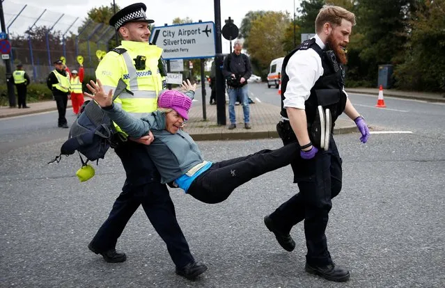 Police officers detain an Extinction Rebellion protester during a demonstration, near London City Airport, in London, Britain, October 10, 2019. (Photo by Henry Nicholls/Reuters)