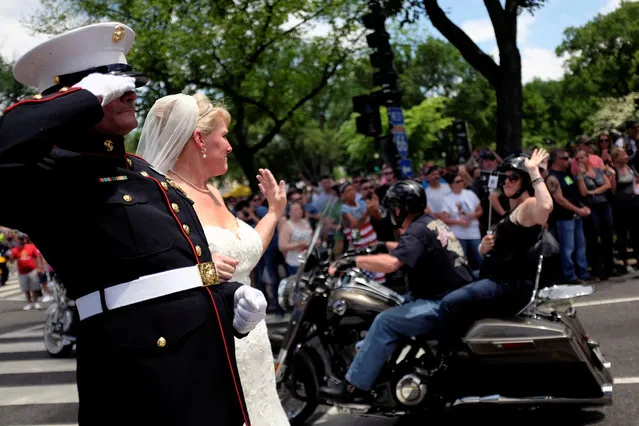U.S. Marine Corp Staff Sgt. Tim Chambers and his bride Lorraine Heist salute and greet motorcyclists participating in Rolling Thunder, the annual ride around Washington Mall to raise awareness for prisoners of war and soldiers still missing in action, in Washington, U.S., May 29, 2016. (Photo by James Lawler Duggan/Reuters)