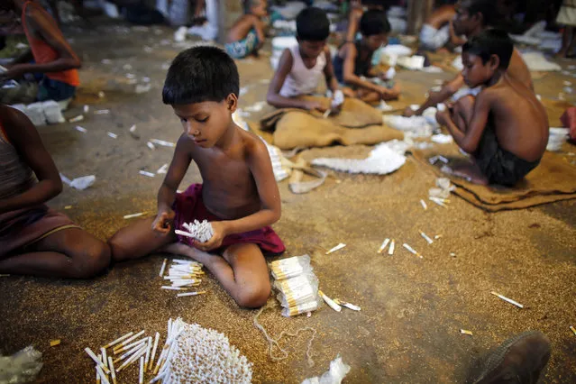 Children fill up empty cigarettes manually with locally grown tobacco in a small bidi (cigarette) factory at Haragach in Rangpur district, Bangladesh July 11, 2013. According to a 2012 study by US-based NGO, Campaign for Tobacco-Free Kids, over 45,000 people in Bangladesh are employed in manufacturing inexpensive cigarettes known as bidis and this number includes ìmany women and children working in household based establishments where they make low wages and live in poverty. (Photo by Andrew Biraj/Reuters)