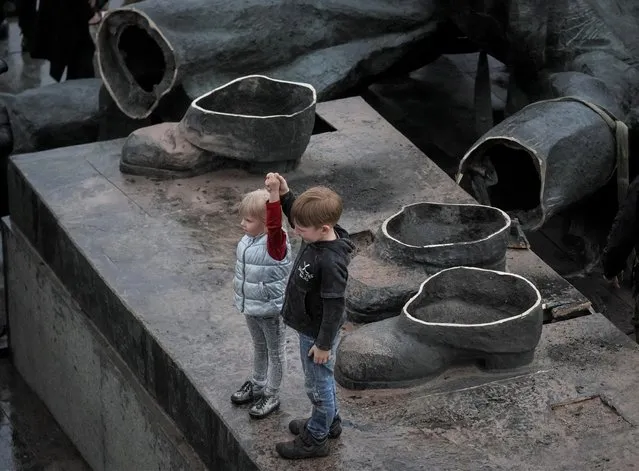 Children depict a Soviet monument to a friendship between Ukrainian and Russian nations after its demolition in central Kyiv, Ukraine on April 26, 2022. (Photo by Gleb Garanich/Reuters)