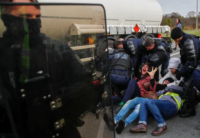 French gendarmes evacuate demonstrators who sit on the road and block full tanker trucks in front of the French oil giant Total refinery in Donges, France, January 2, 2020. (Photo by Stephane Mahe/Reuters)