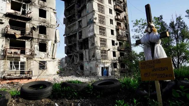 A grave is pictured in front of destroyed residential buildings in Mariupol on May 31, 2022, amid the ongoing military action in Ukraine. (Photo by AFP Photo/Stringer)